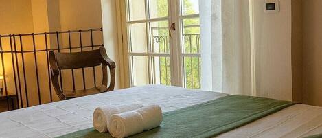 Una habitación de hotel con una cama, una ventana con cortinas, una silla y vistas a zonas verdes.