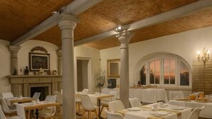Un comedor con piso a cuadros, sillas blancas y mesas dispuestas para una comida.