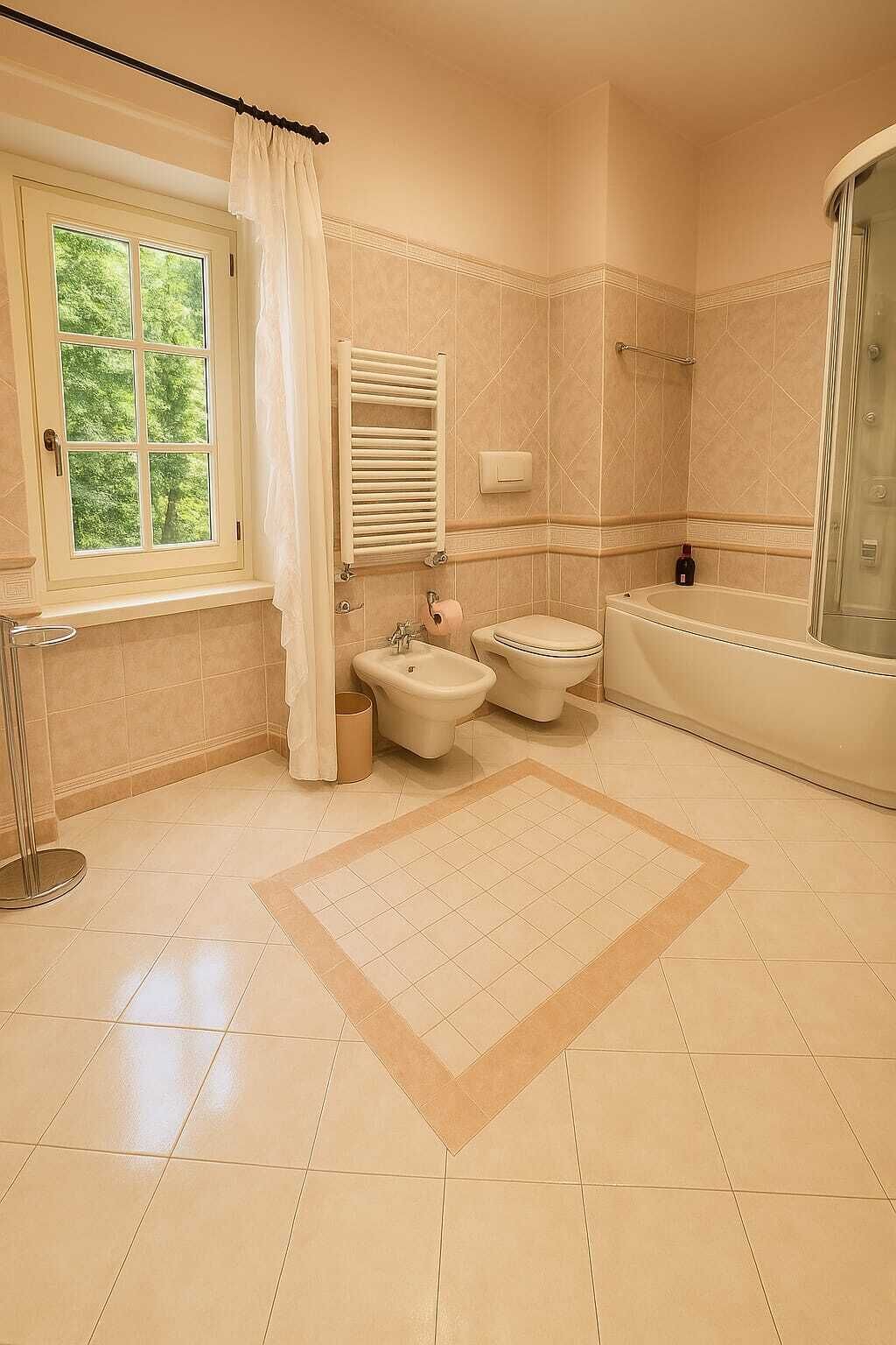 Ein Badezimmer mit Badewanne, Toilette, Bidet und einem Fenster mit Vorhang.