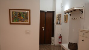 A hallway with a wooden door, a fire extinguisher, a bench, and a coat rack.