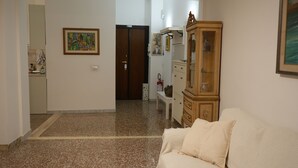 A living room with a sofa, a cabinet, and a door leading to another room.