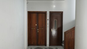 A hallway with two wooden doors, one with a control panel, and a checkered floor.