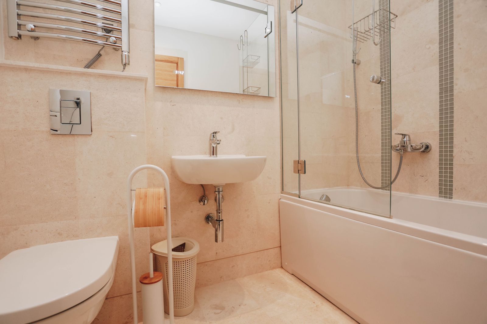 Un baño moderno con inodoro, lavamanos y ducha con mampara de vidrio.