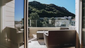 Een balkon met rieten meubilair en uitzicht op een heuvel met gebouwen op de achtergrond.