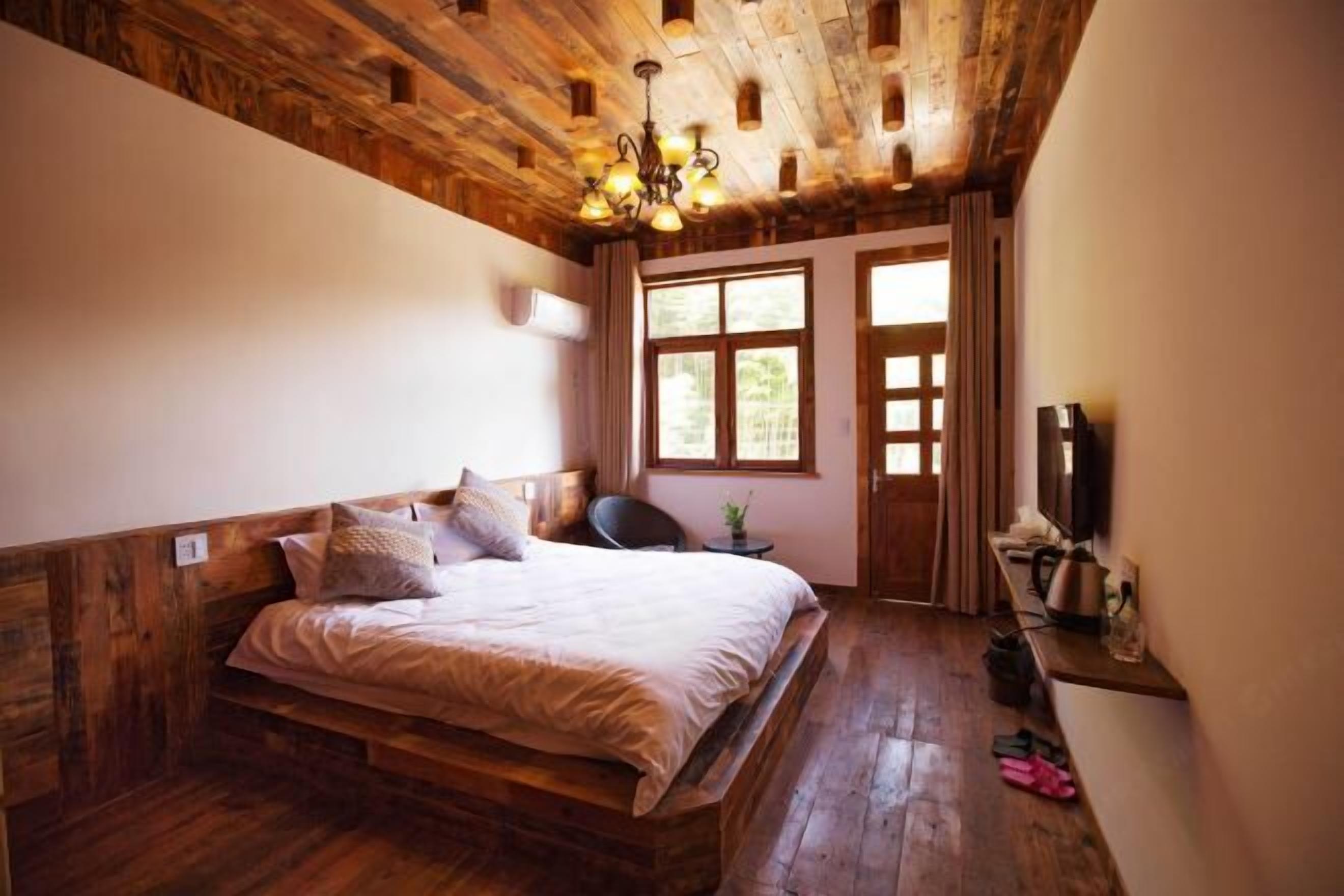 A wooden-paneled bedroom with a bed, a desk, and a window.
