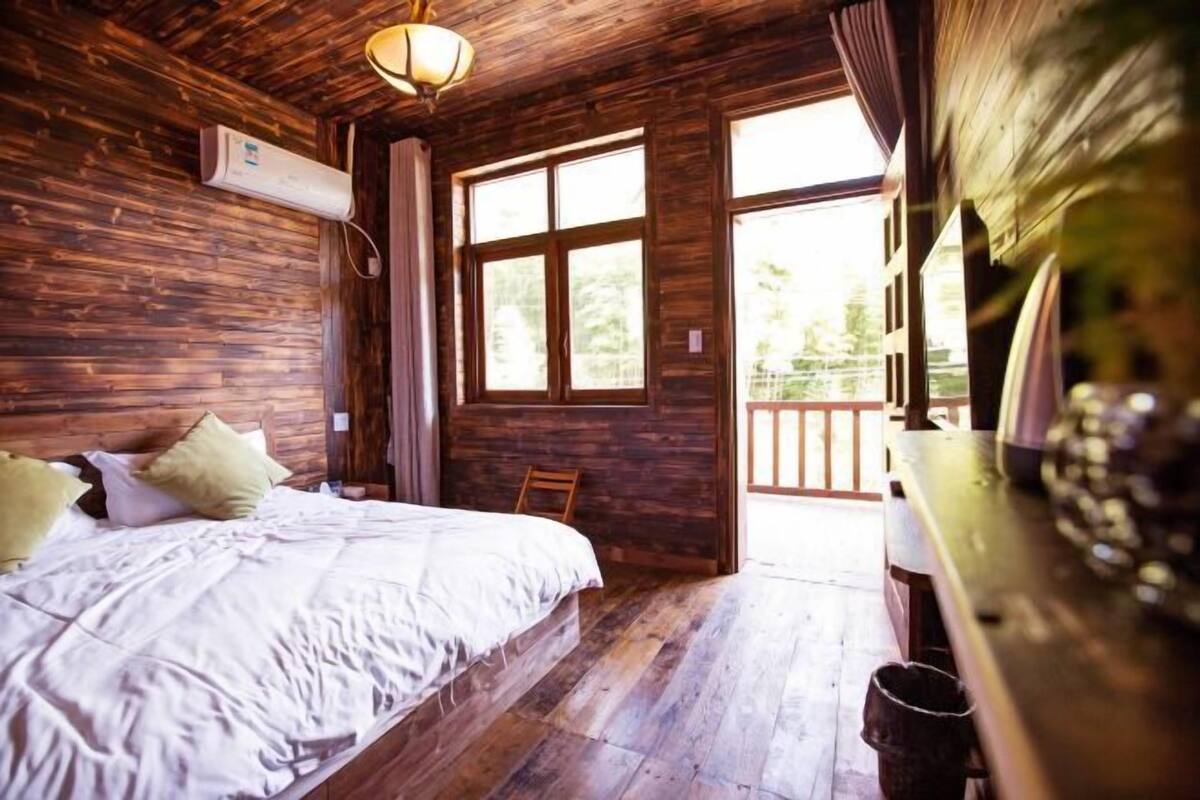Una habitación de madera con una cama, una ventana y una puerta que da al exterior.