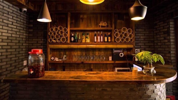 Een bar met houten planken, hangende lampen en een potplant.