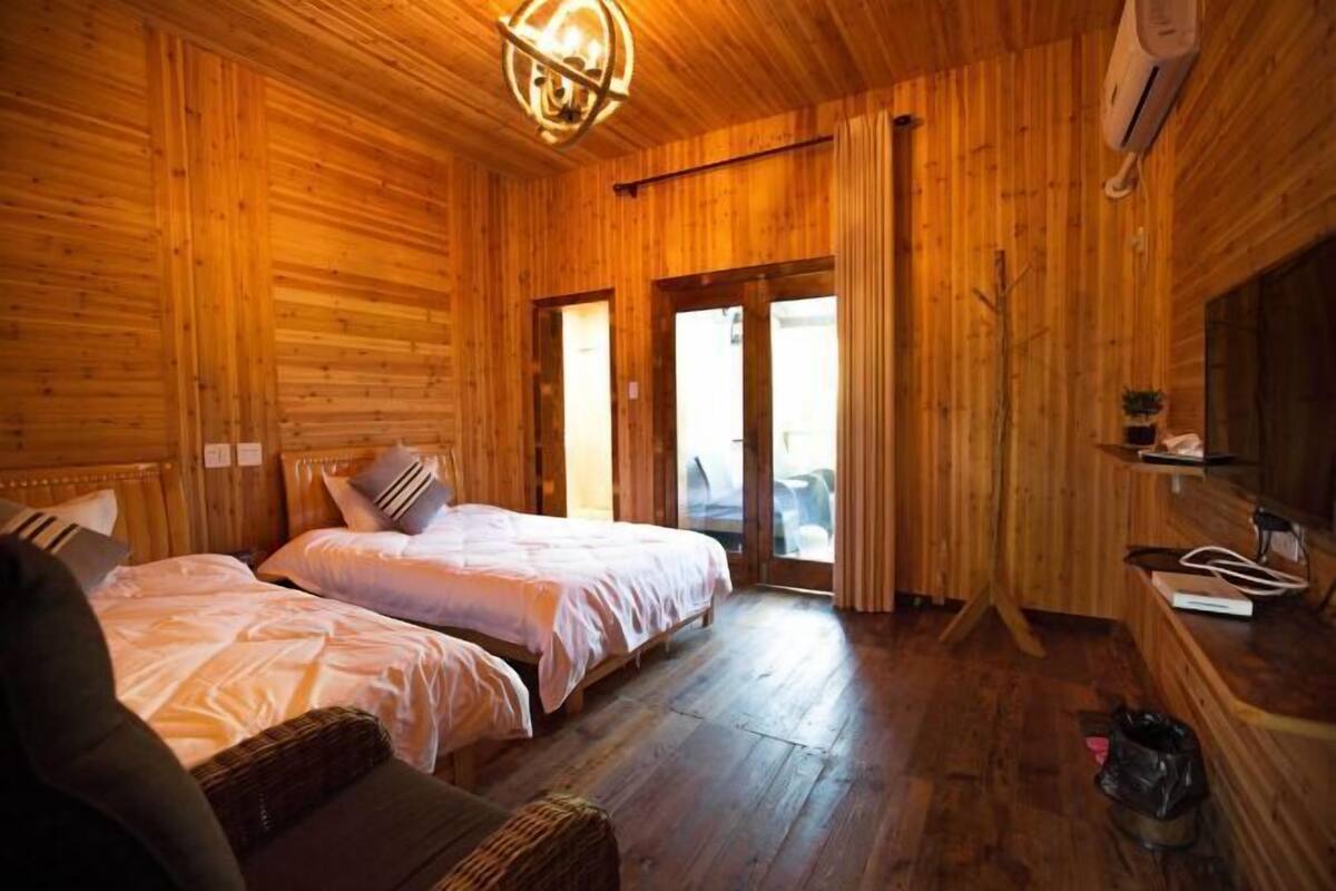 Una habitación de cabaña de madera con dos camas, un sofá y una mesita.