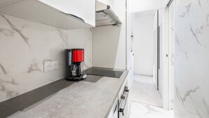 Una cucina moderna con una macchina per il caffè, forno integrato e una parete rivestita in marmo.