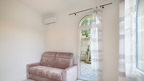 Una stanza con un divano, una porta scorrevole in vetro e un condizionatore.