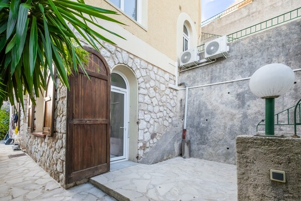 A stone building with a wooden door, a small balcony, and a street lamp.