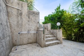 A concrete staircase with metal railings, a metal folding chair, and a paved stone floor.