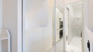 Un interno moderno con un divisorio in vetro, una zona cucina e un pavimento in marmo.