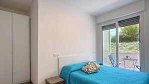 A bedroom with a bed, a small stool, a wardrobe, and a balcony with a table and chairs. - Dimora Venus - Comfort moderno sul mare (Fossacesia)