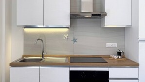 A modern kitchen with white cabinets, a stainless steel sink, a built-in oven, and a wooden countertop. - Dimora Venus - Comfort moderno sul mare (Fossacesia)