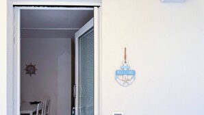 A room with a dining table, chairs, a door, and a wall-mounted welcome sign. - Dimora Venus - Comfort moderno sul mare (Fossacesia)