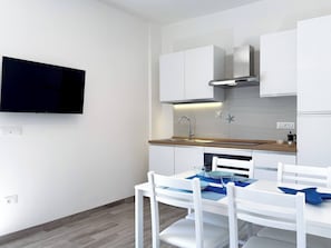 Une cuisine moderne avec des meubles blancs, un plan de travail en bois, une hotte en acier inoxydable et un lave-vaisselle encastré.