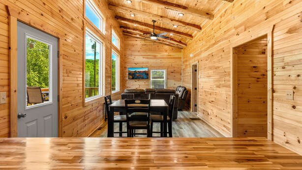 A wooden cabin with a dining area, a ceiling fan, and large windows. - Trailer Parking/Hot Tub/King Size Beds/Mt Views (Stanton)
