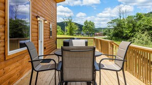 A wooden deck with four chairs and a table, overlooking a grassy area and hills. - Trailer Parking/Hot Tub/King Size Beds/Mt Views (Stanton)