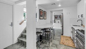 A modern kitchen with a white countertop, bar stools, and a built-in oven.
