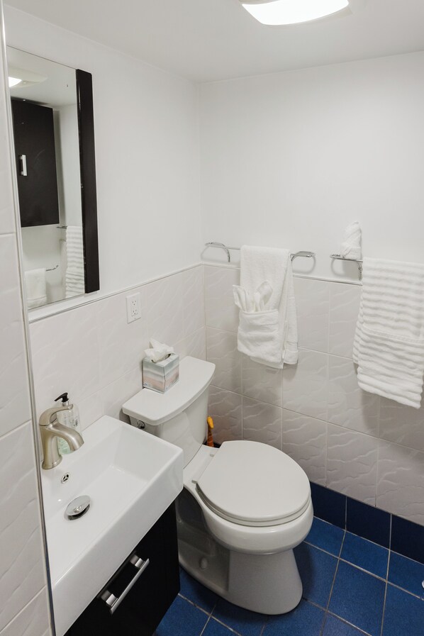 A bathroom with a white sink, toilet, and blue-tiled floor.