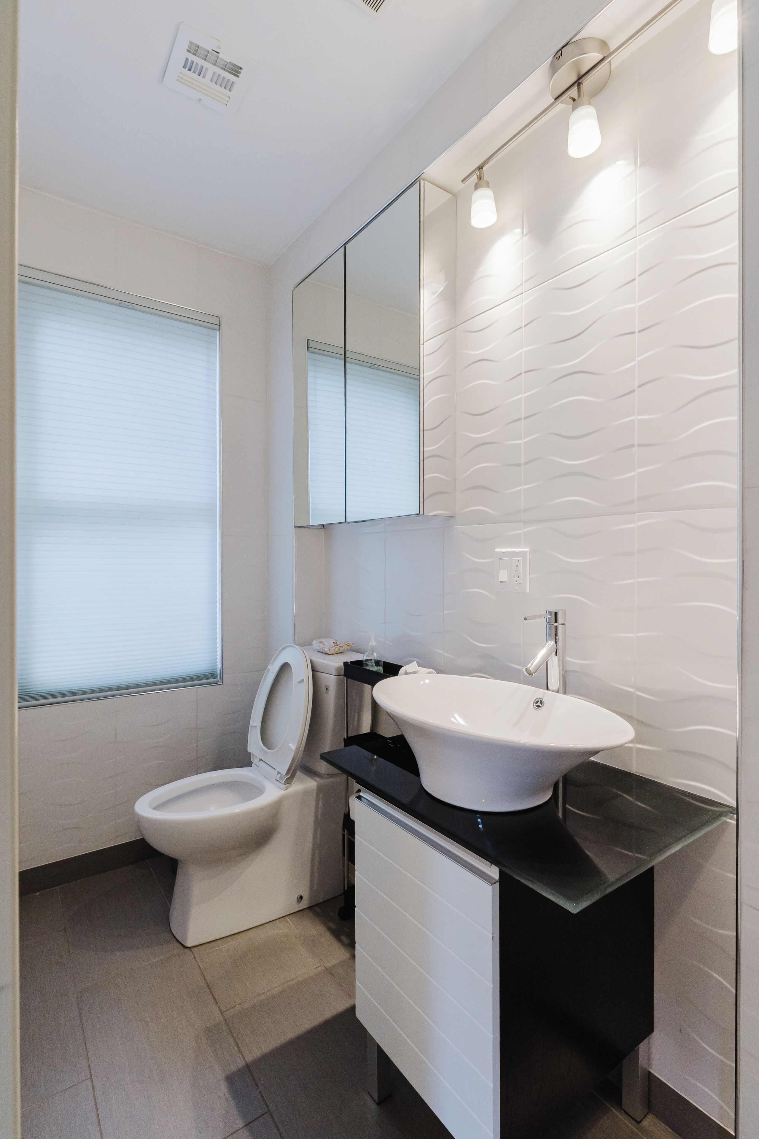 A modern bathroom with a toilet, sink, and mirror.