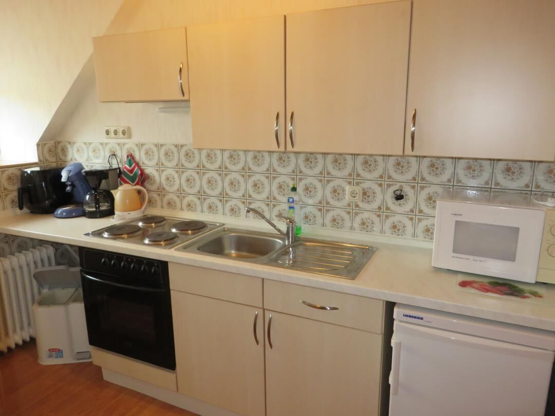 A kitchen with a stove, sink, microwave, and cabinets.