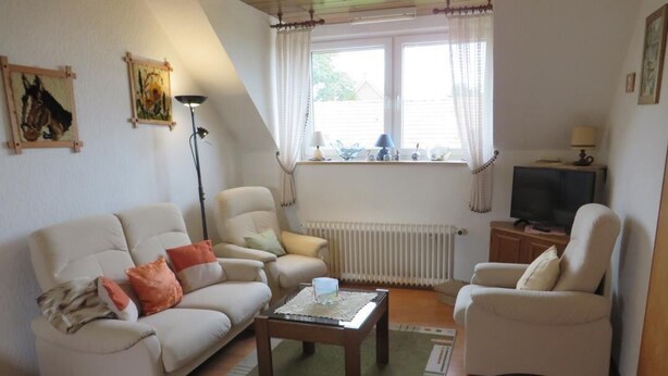 A living room with a sofa, armchairs, a coffee table, and a television. - NEW! Vacation apartment directly on the dike (Dornum)