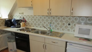 A kitchen with a stove, sink, microwave, and cabinets. - NEW! Vacation apartment directly on the dike (Dornum)