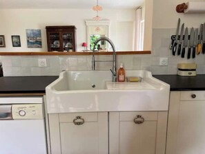 A kitchen with a white sink, a dishwashing machine, and a knife rack.