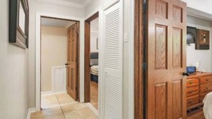 A hallway with wooden doors, a tiled floor, and a dresser with drawers.