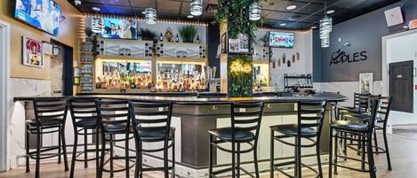 A bar area with multiple stools, a bar counter, and a television screen displaying a news program.