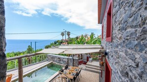 A stone building with a pool, outdoor seating, and a view of the ocean. - Fajã Stone House 1  by LovelyStay (Arco Da Calheta)