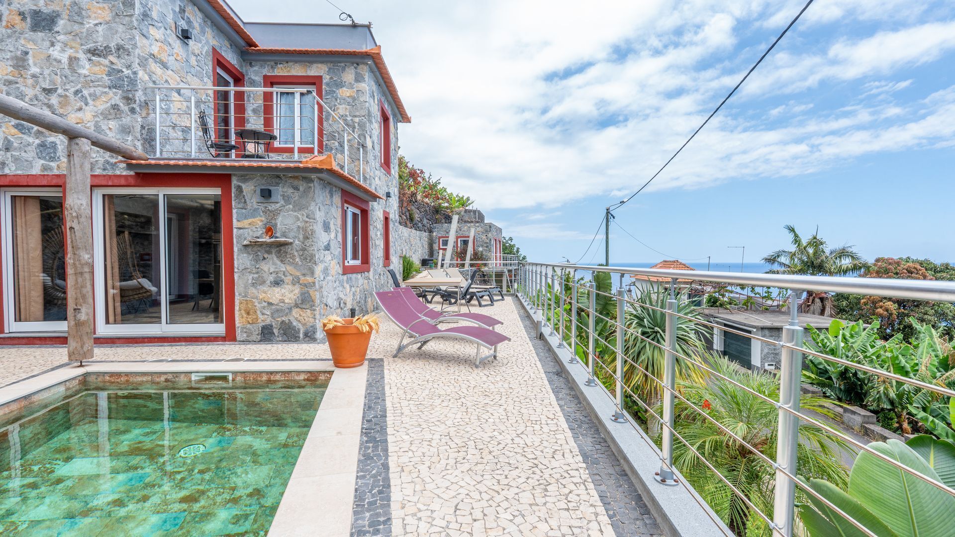 A stone building with a pool, outdoor seating, and a view of the sea.