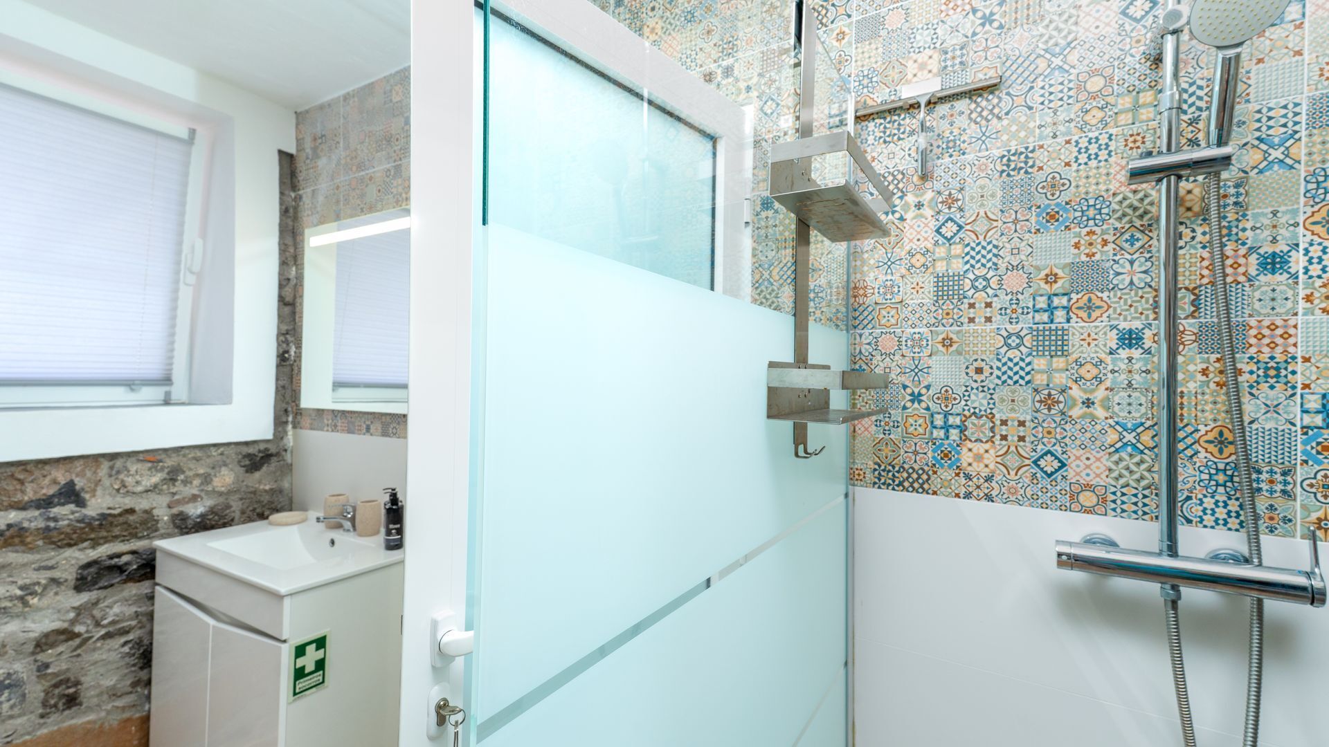 Une salle de bain avec une douche, un lavabo, une fenêtre et une porte.