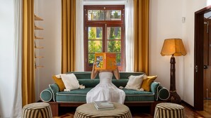 A room with a green sofa, a lamp, a book, and a window with curtains. - Eden Funchal by LovelyStay (Funchal)