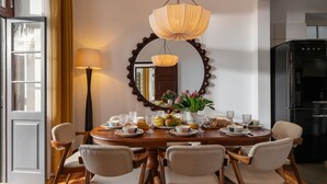 A dining area with a wooden table set for six, surrounded by six chairs. A large mirror with a decorative frame hangs above the table. - Eden Funchal by LovelyStay (Funchal)