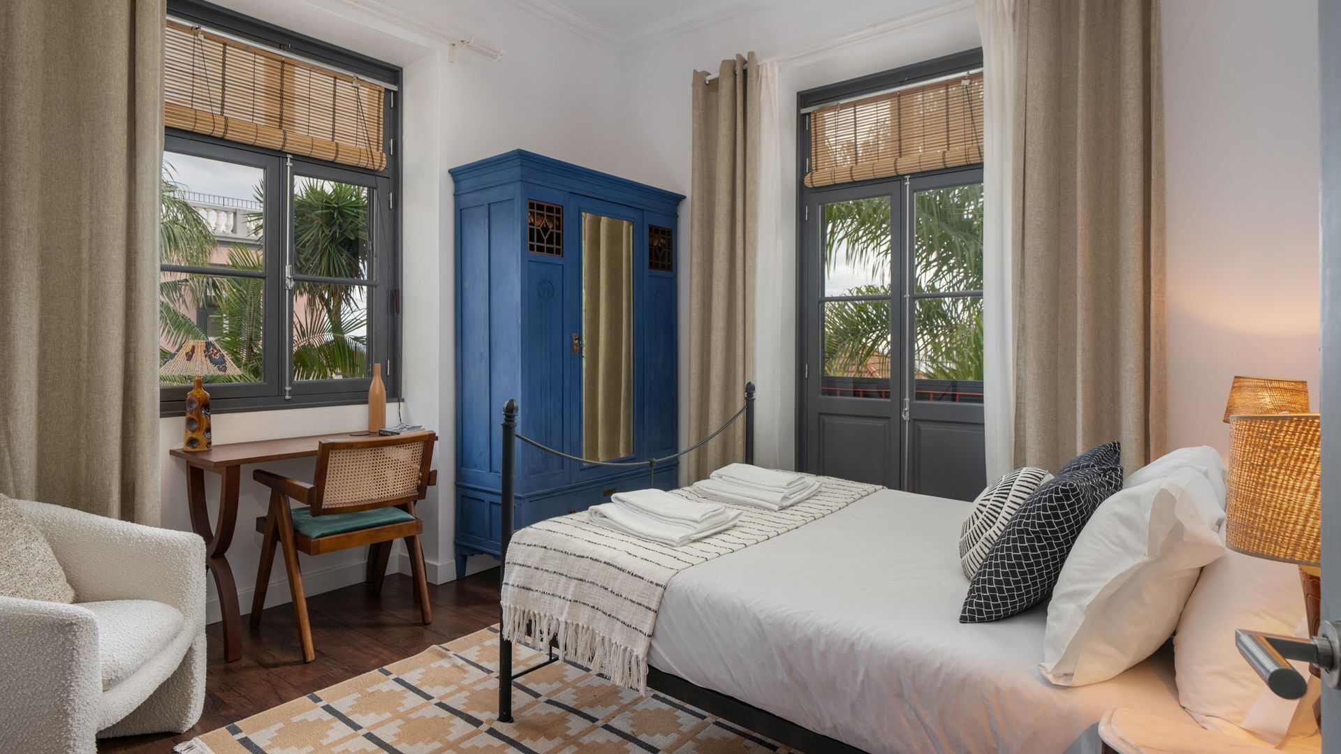 A hotel room with a bed, a desk, a chair, and a wardrobe.
