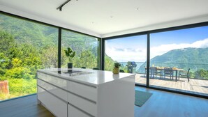 Eine moderne Küche mit einer großen Kochinsel, großen Fenstern und Blick auf eine Berglandschaft.