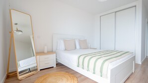 A bedroom with a bed, a nightstand, a mirror, and a wardrobe. - Hygge Madeira by LovelyStay (Canico)