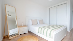 A bedroom with a bed, a nightstand, a mirror, and a wardrobe.