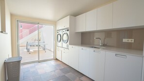 A modern kitchen with a built-in washing machine, a sink, and a trash bin.
