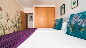 A bedroom with a bed, a wooden wardrobe, and a door leading to another room. - Delmar by LovelyStay (Caniço)