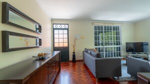 Un salon avec un canapé, un téléviseur et un meuble en bois.