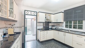 Une cuisine moderne avec des armoires blanches, des comptoirs noirs et une hotte de cuisinière en acier inoxydable.