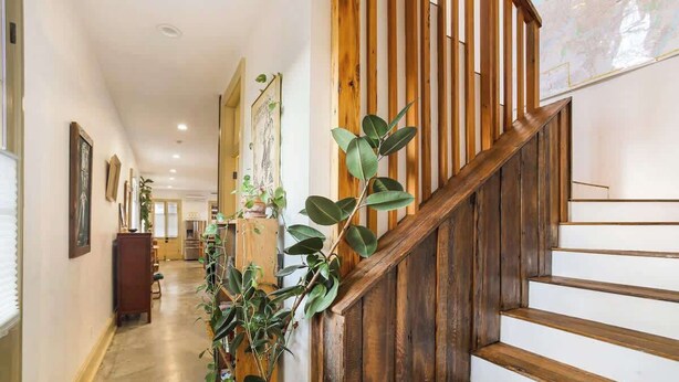 A wooden staircase with a white wall and a plant on the left. - Charming Historic House w Heated Pool & Hot Tub 5 BR|3 BA (New Orleans)