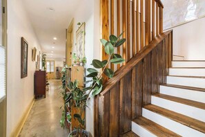 A wooden staircase with a white wall and a plant on the left.