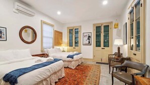 A hotel room with two beds, a desk, a chair, and a patterned rug. - Charming Historic House w Heated Pool & Hot Tub 5 BR|3 BA (New Orleans)