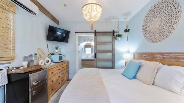 A bedroom with a bed, dresser, TV, and decorative wall piece. - Casa de Teo (St. Augustine)