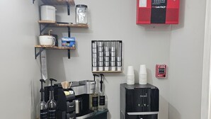 Et tekøkken med kaffemaskine, vanddispenser og brandalarm.